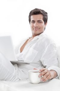 Smiling men sitting on sofa using laptop.