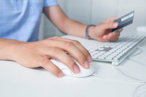 Close up of businessman hand using computer and holding credit card.indoor.shopping online concept