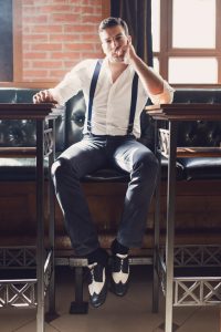 Portrait of an attractive and elegant young man sitting at the gentlemen's bar and looking at the camera.